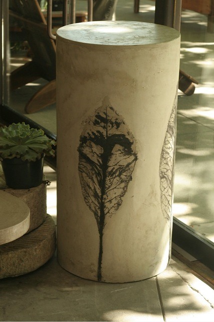 tall circular concrete cocktail table or pillar with black leaf design on sides 