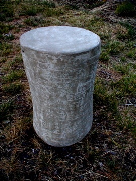 organic shaped round concrete side table in light brown with subtle horizontal line design on sides on lawn
