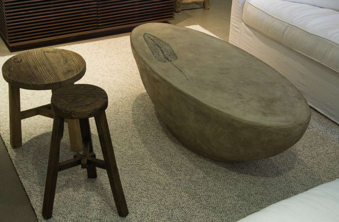 light brown oval concrete coffee table with botanical leaf design on top in rustic living room environment