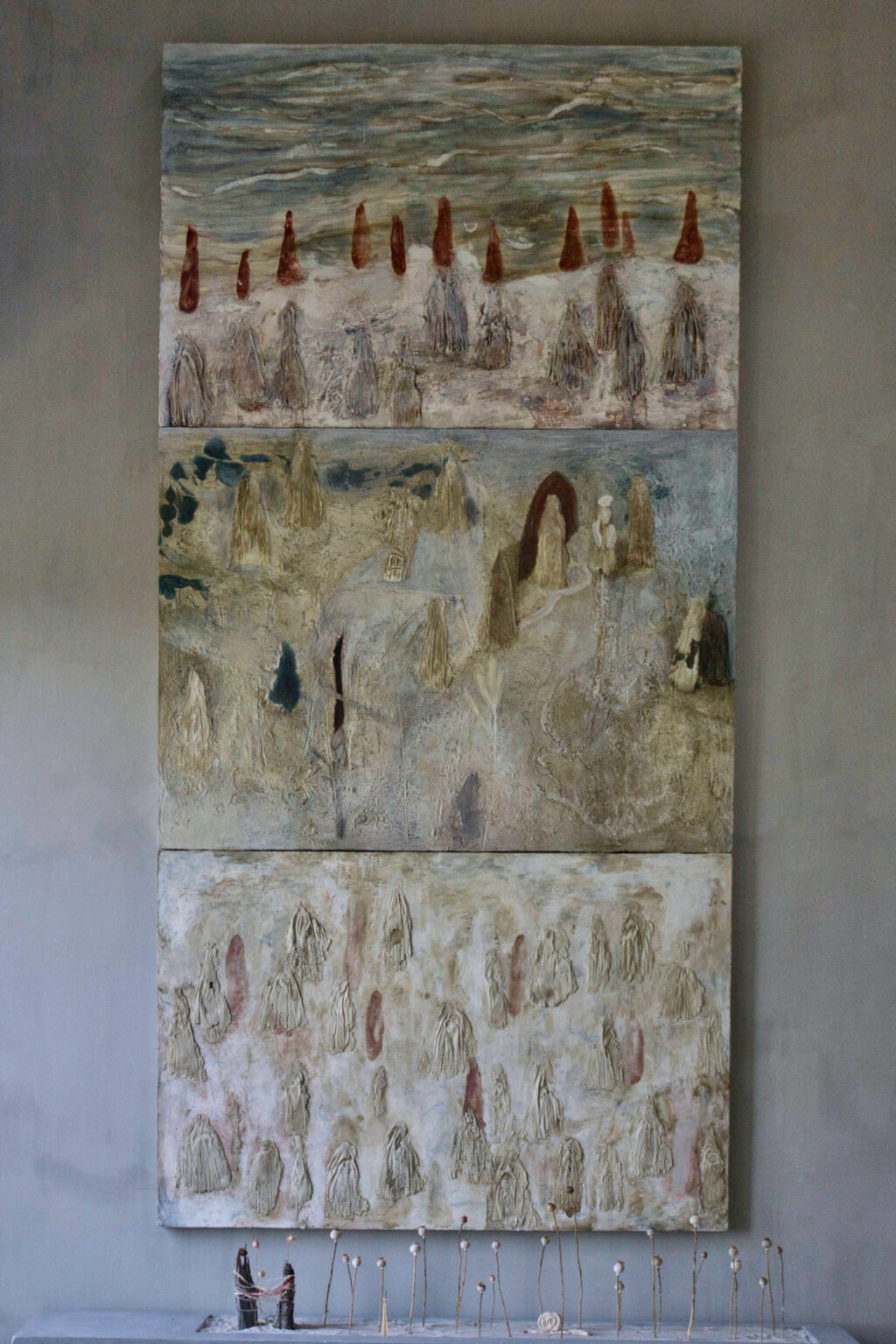 Triptych of colorful large cement paintings one on top of another with corn husk impressions and various reds, blues, and greens
