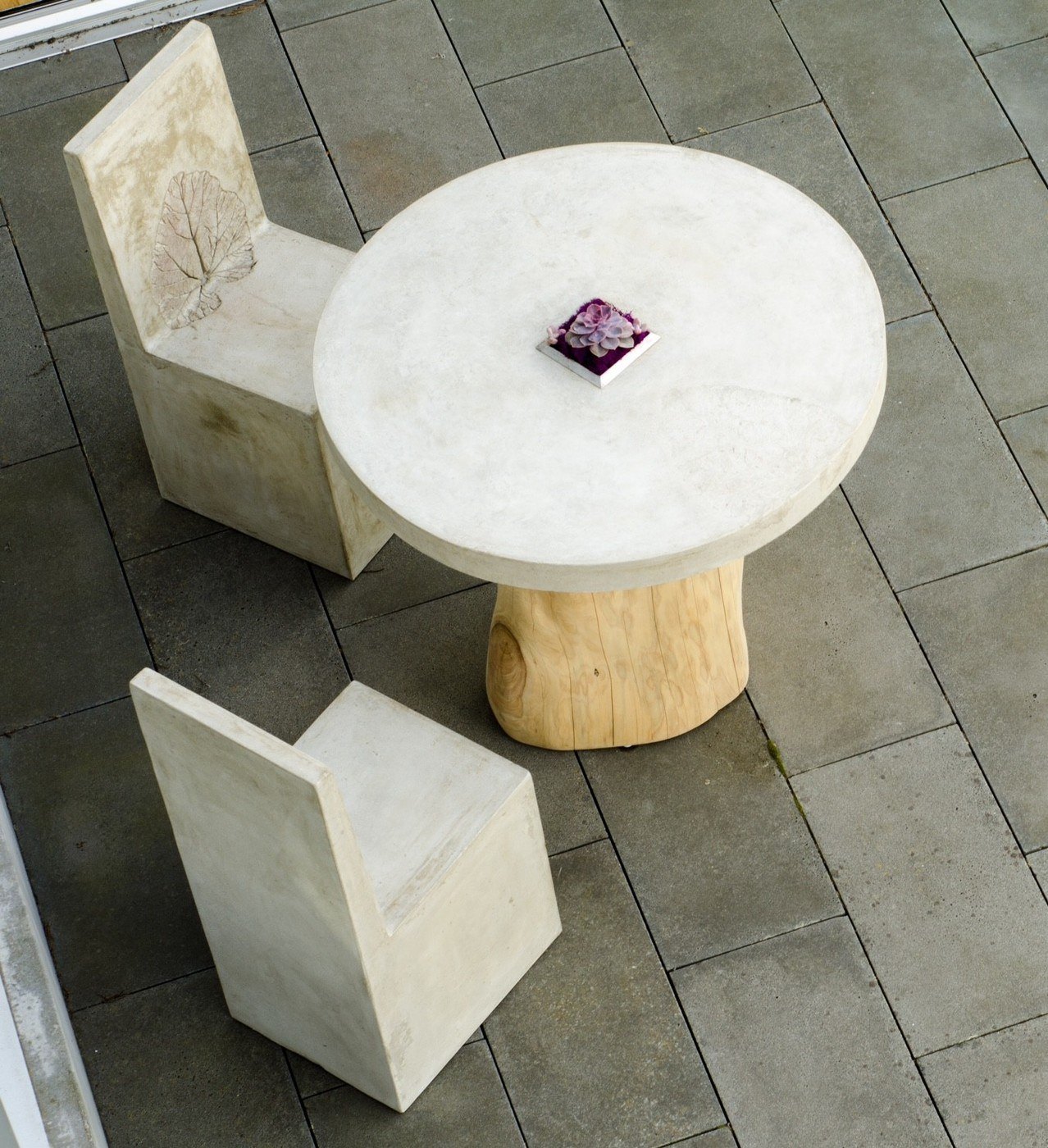 concrete dining table on patio with two concrete chairs with rhubarb leaf imprints