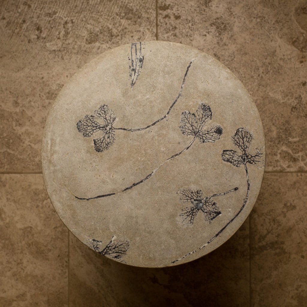 Top shot of round concrete end table with grey leaf impressions