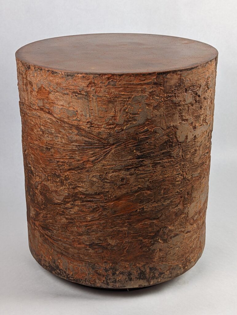 Organic and unique, textured rust-colored concrete side table with botanical corn lily impressions