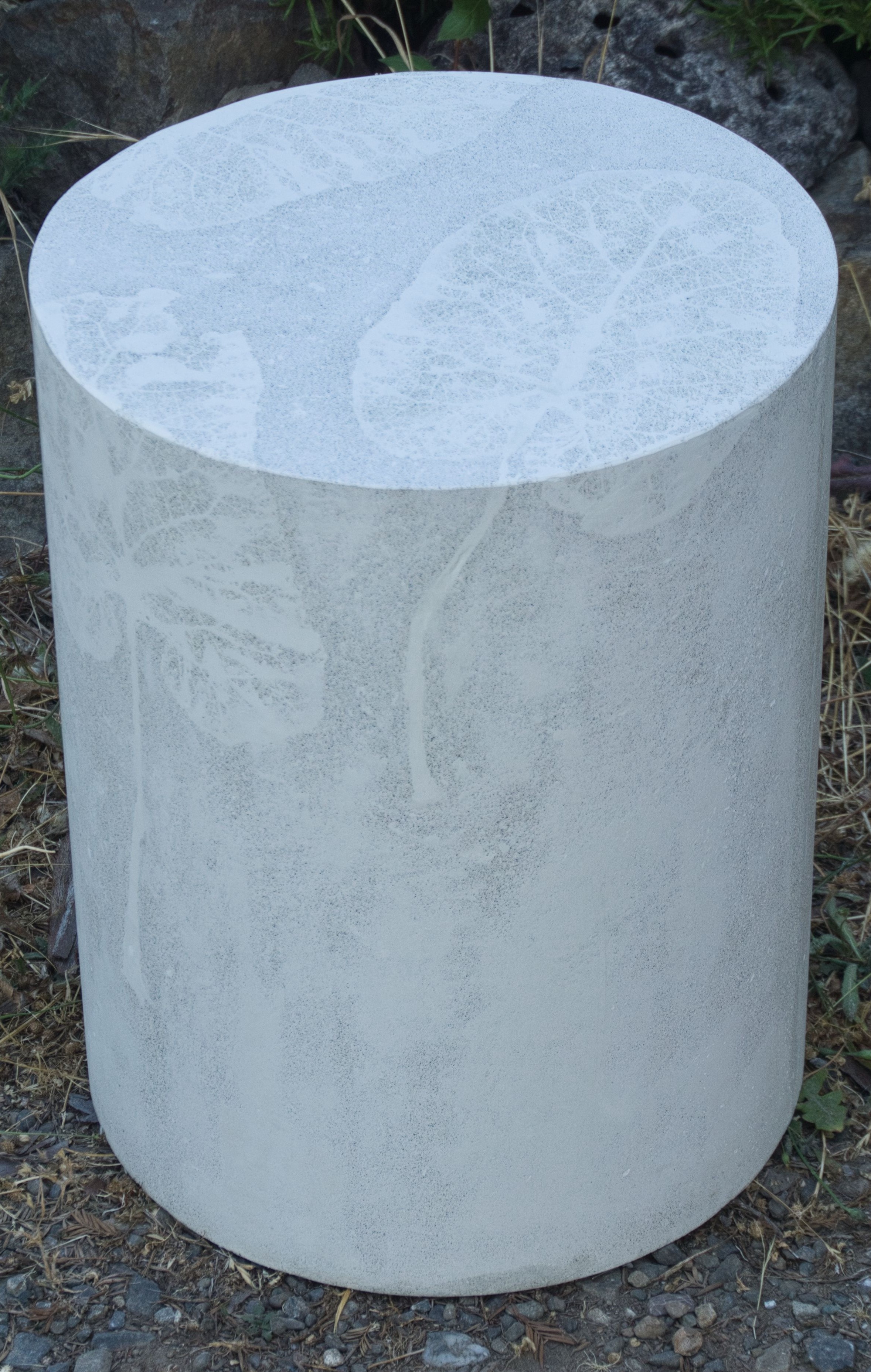 white round concrete stool with subtle white leaf design on top and sides