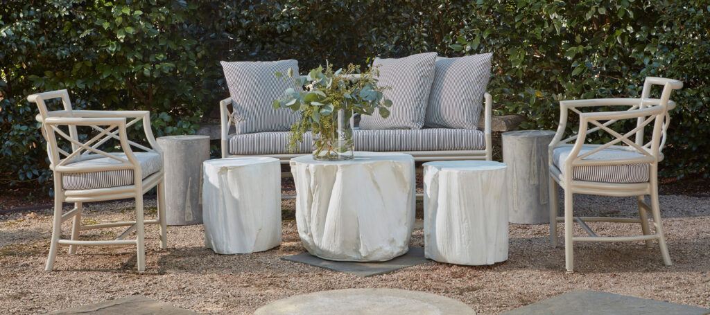 Outdoor living room environment with sculptural concrete palm stump coffee tables and corn husk round side tables in background