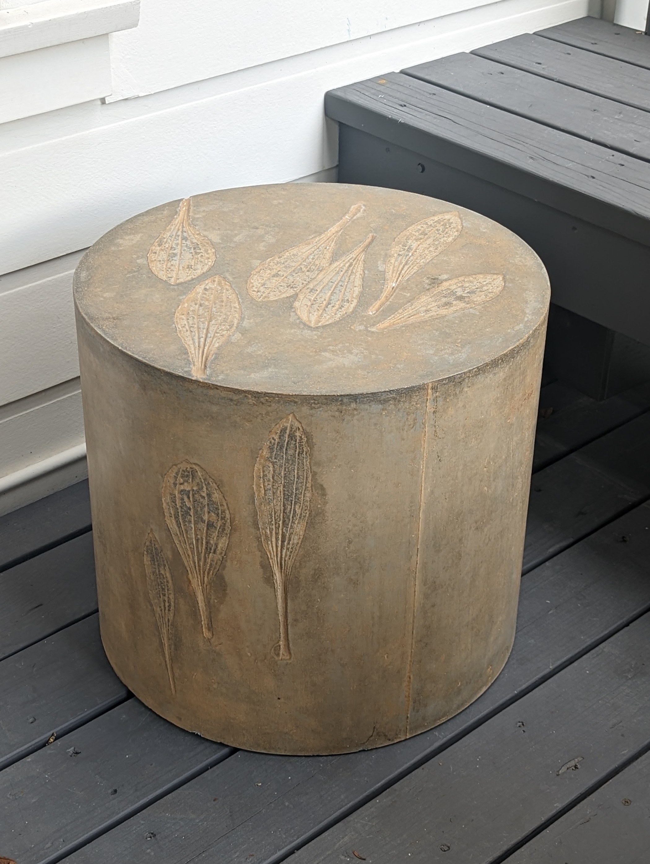 Brown and gold concrete cylindrical coffee table with plantain leaf impressions