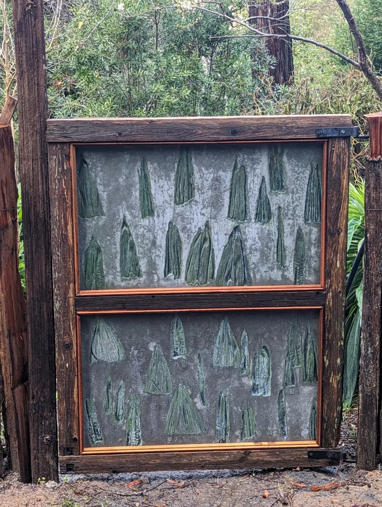 Gate with wood framing and concrete panels with corn imprints with green highlights