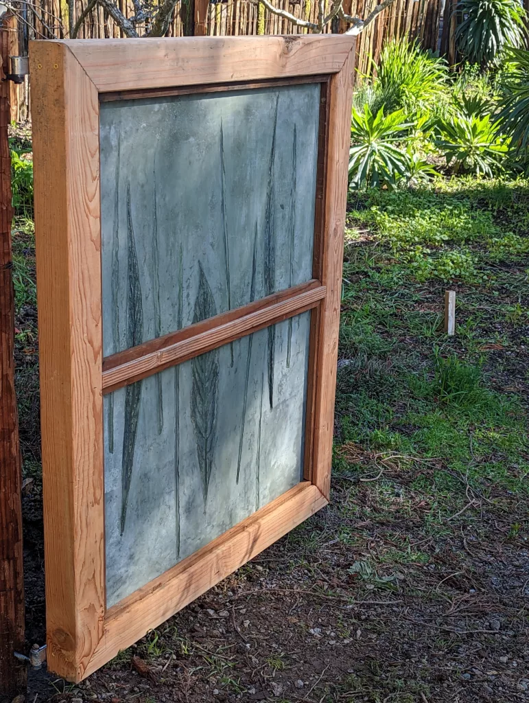 Gate with wood framing and concrete panels with grass and echium leaf imprints with green highlights Angle shot