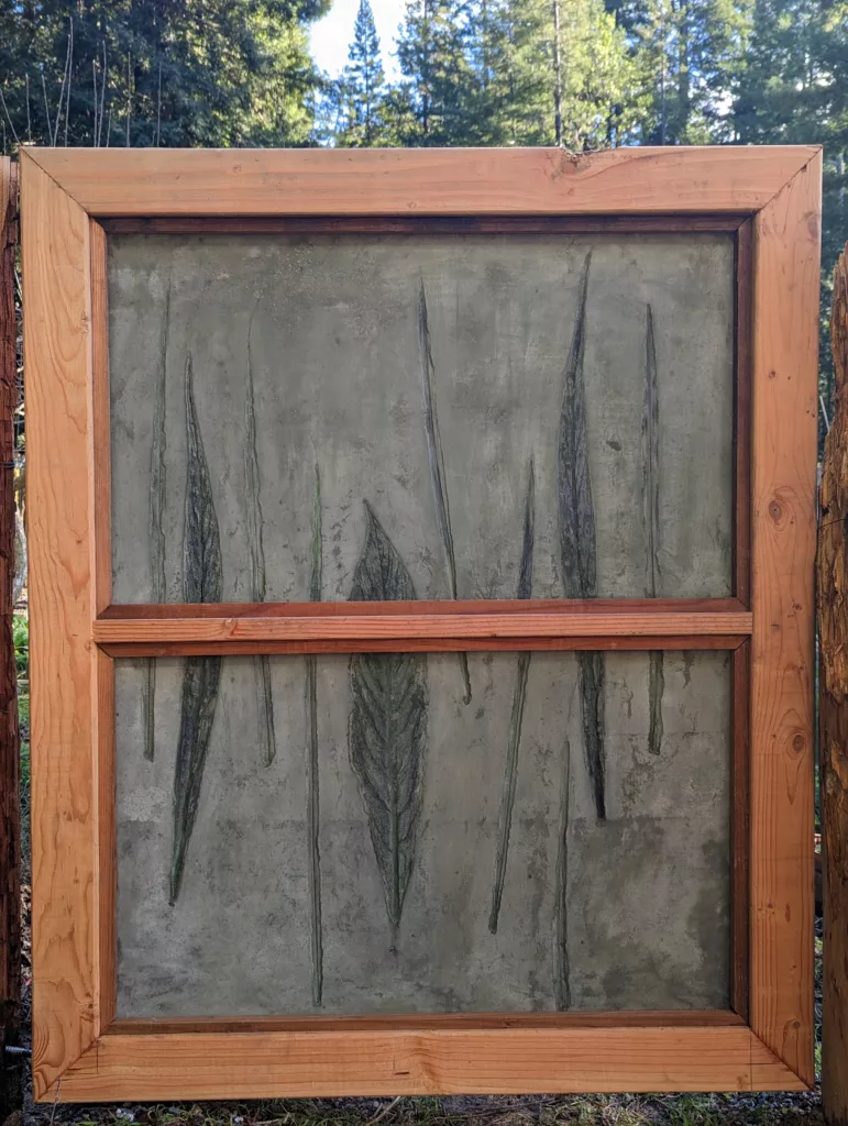 Gate with wood framing and concrete panels with grass and echium leaf imprints with green highlights