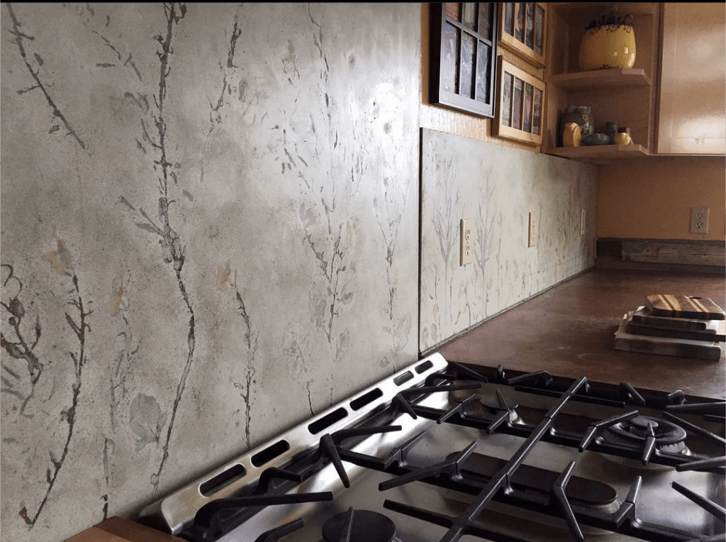 concrete backsplash over wood stove and counters with wabi-sabi botanical leaf designs and outlet knockouts